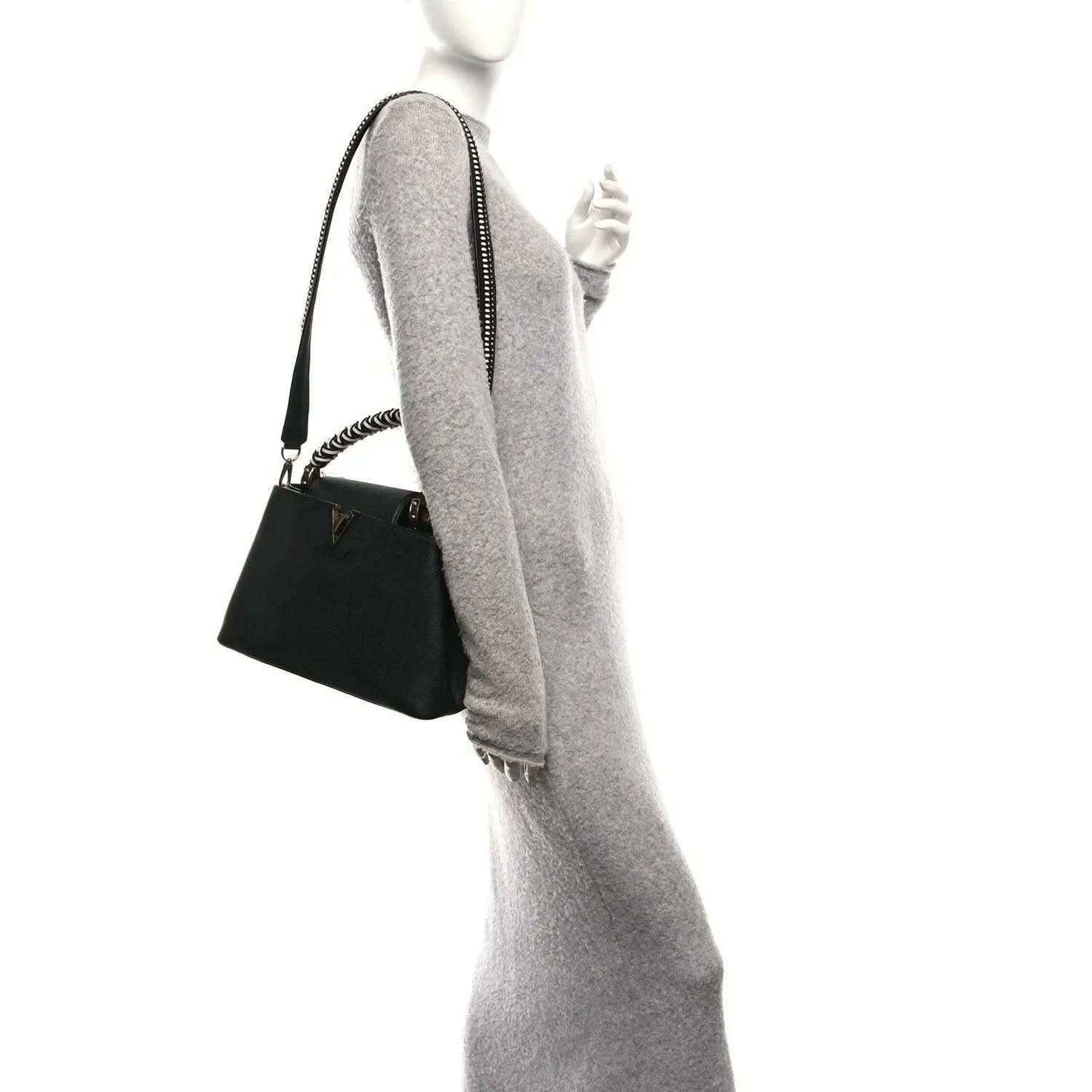 Black leather handbag with braided chain strap, worn crossbody