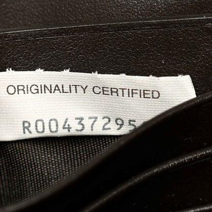 White label with authenticity text inside dark leather clutch