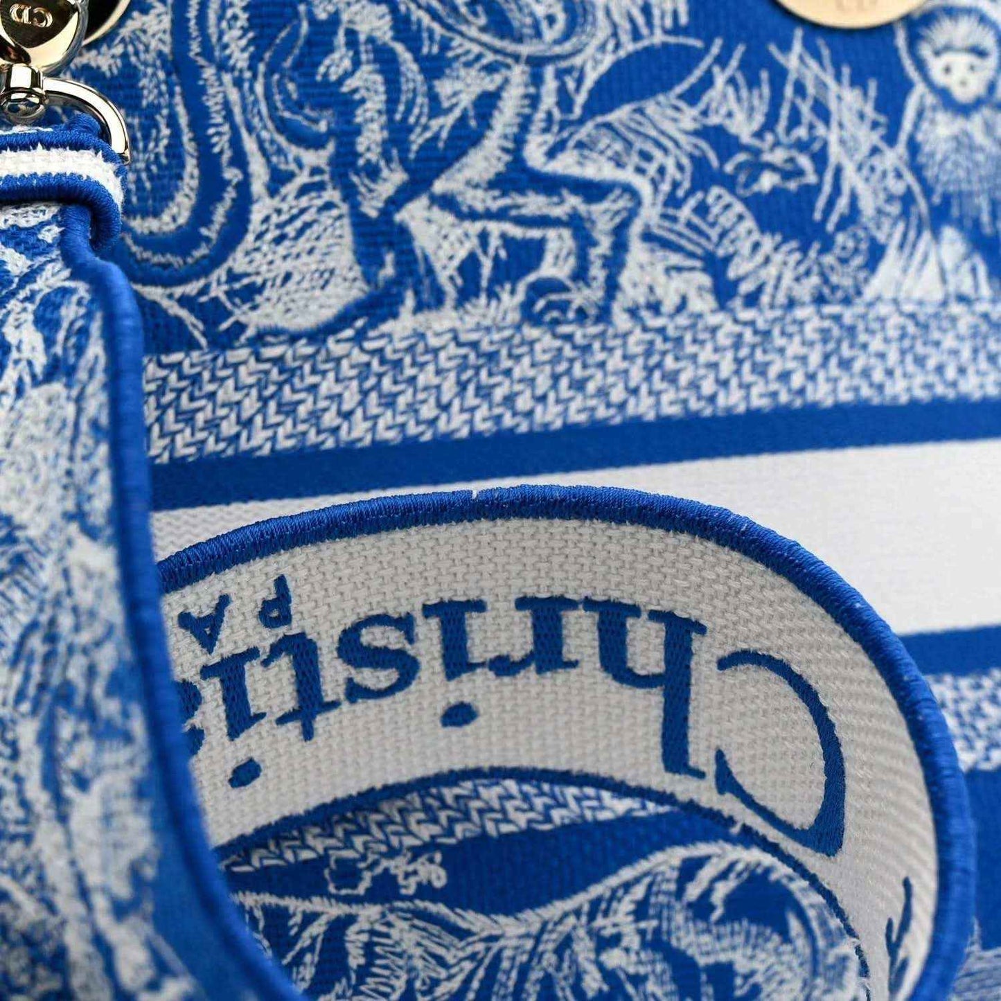 Blue-and-white toile bag detail with Dior logo emblem and top edge