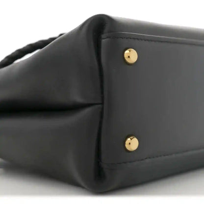 Black leather small shoulder bag with gold-tone snap buttons on front flap.