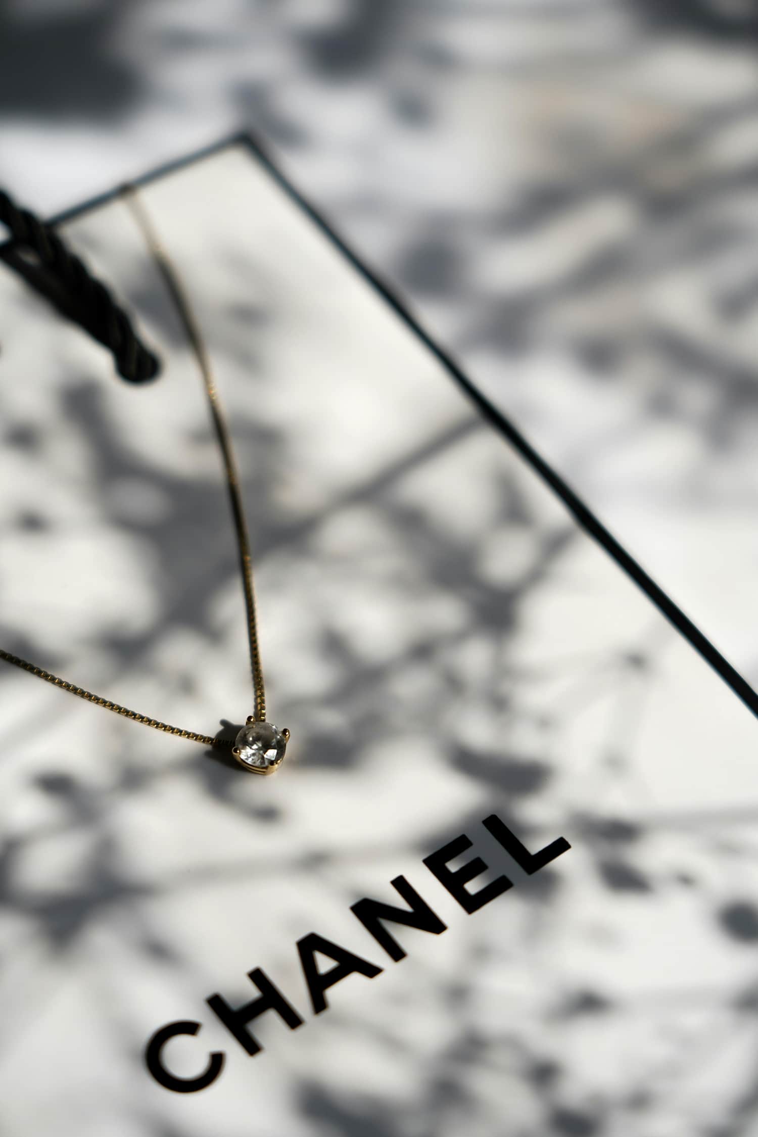 Chanel necklace on a reflective surface with blurred background