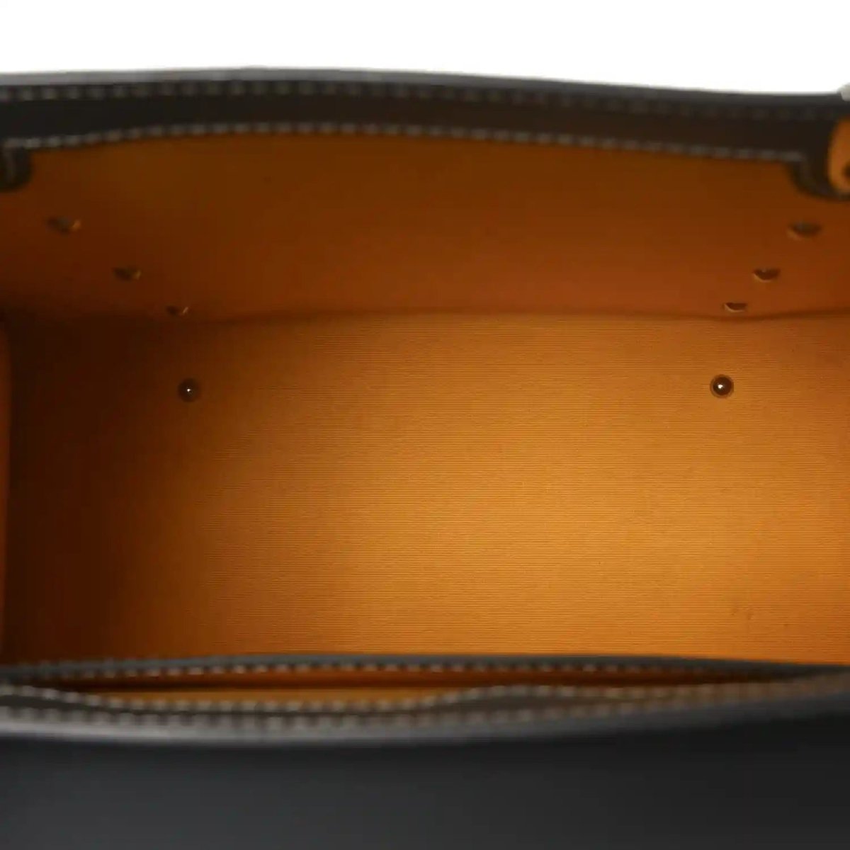 Tan fabric interior lining with stitched edge and metal rivets inside the bag