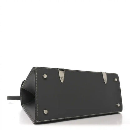 Black leather bottom panel of top-handle bag with metal studs and stitched edges
