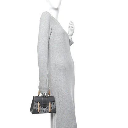 Grey mini Saigon bag on shoulder strap, patterned flap and leather edges.