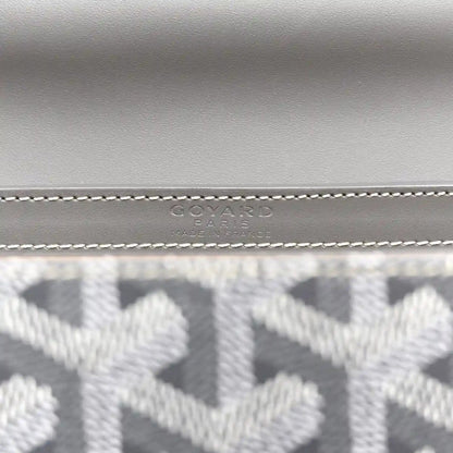 Grey canvas mini Saigon bag close-up of stitched logo emblem on the flap.