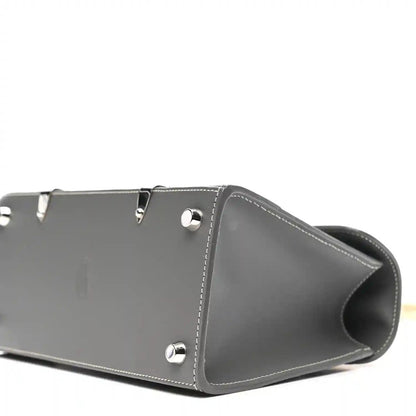 Grey leather mini Saigon bag side view with metal studs and crossbody strap.