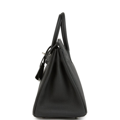 Black leather Birkin handbag from side view with top handles and minimal exterior hardware.
