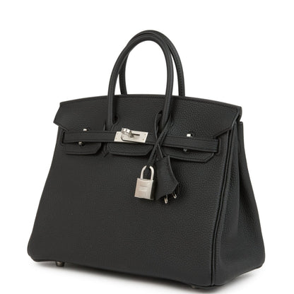 Black leather handbag with top handles, front flap closure, and hanging lock charm.