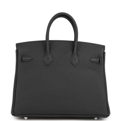 Black tote-style handbag with structured front, top handles, and embossed pocket details.