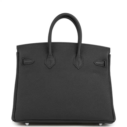 Black tote-style handbag with structured front, top handles, and embossed pocket details.