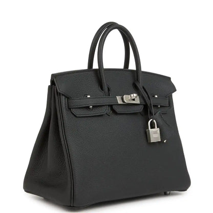 Black leather handbag with structured top handles, front flap, and brushed palladium clasp.
