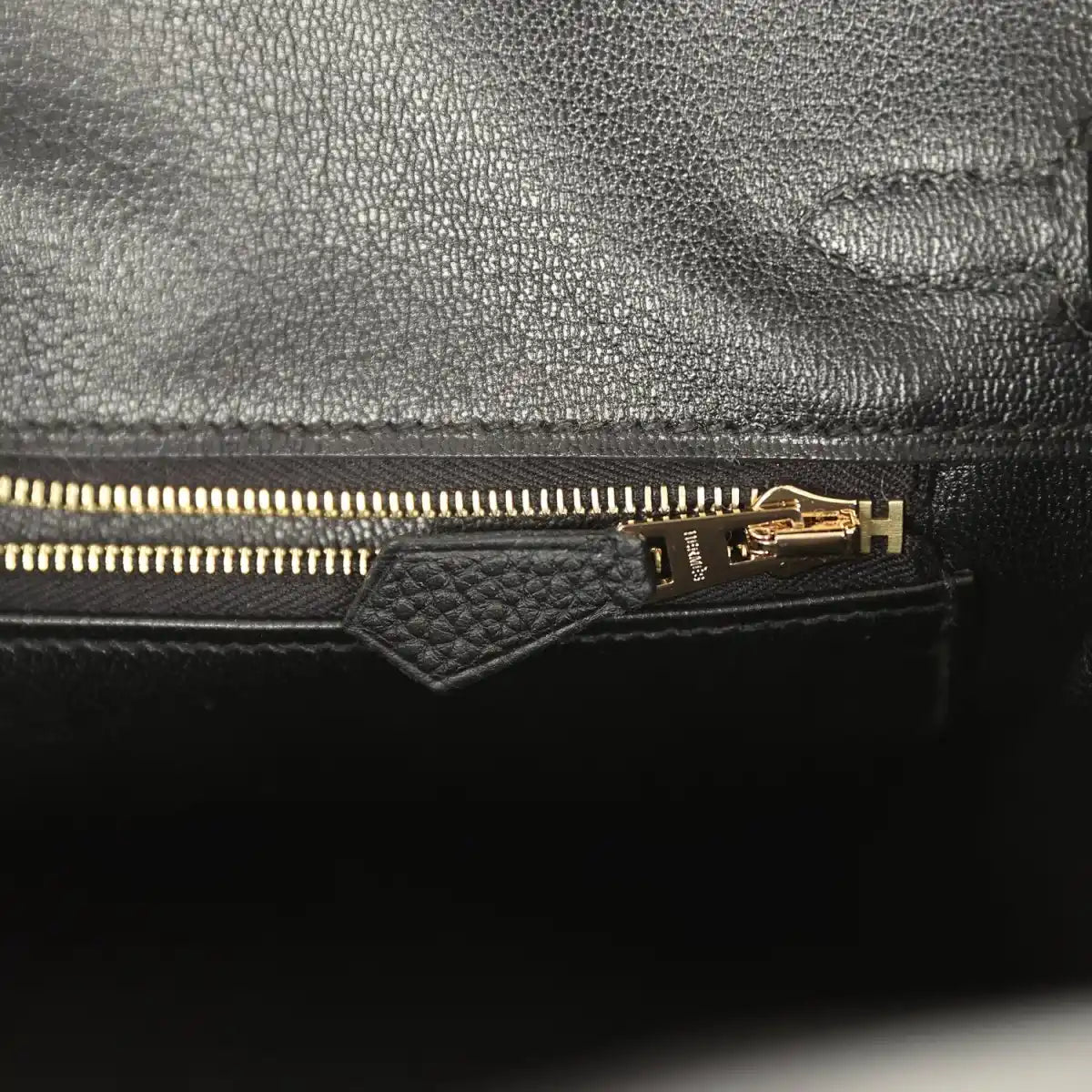 Black leather handbag interior with gold zipper and pull tab