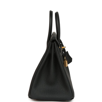 Black leather handbag side view with gold hardware and top handles