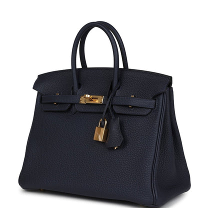Hermes Birkin 25 handbag in dark blue with front clasp and gold lock charm, side view.