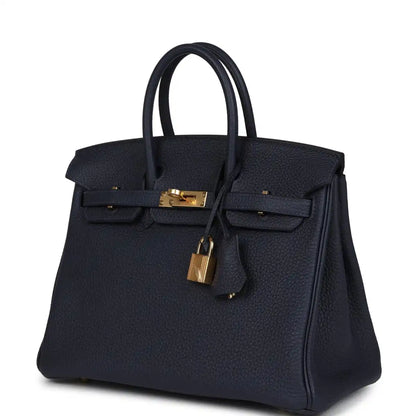Hermes Birkin 25 handbag in dark blue with front clasp and gold lock charm, side view.