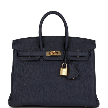 Hermes Birkin 25 handbag in dark blue Togo leather with gold hardware and top handles.