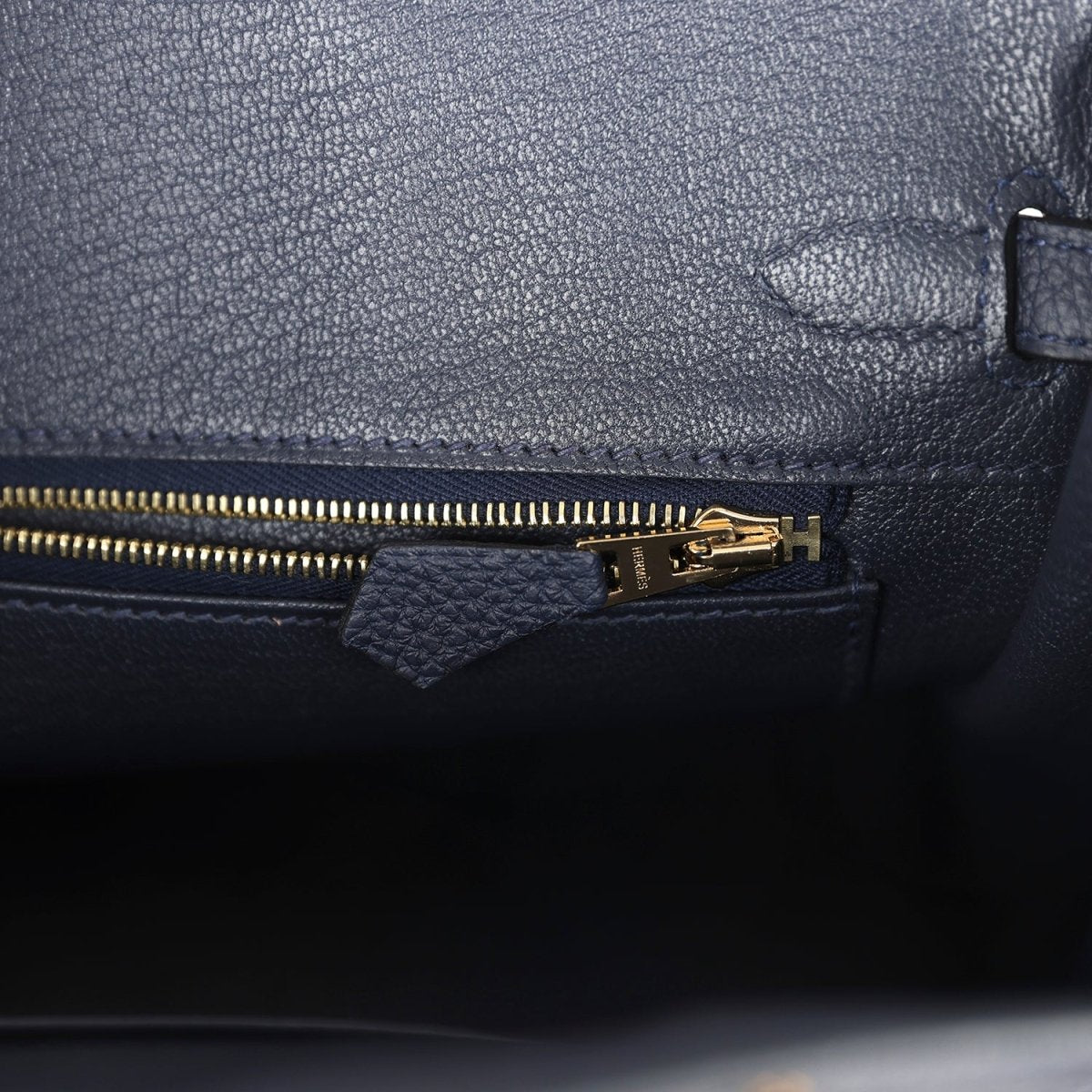 Hermes Birkin 25 handbag with dark blue leather zipper pocket and gold zipper pull.