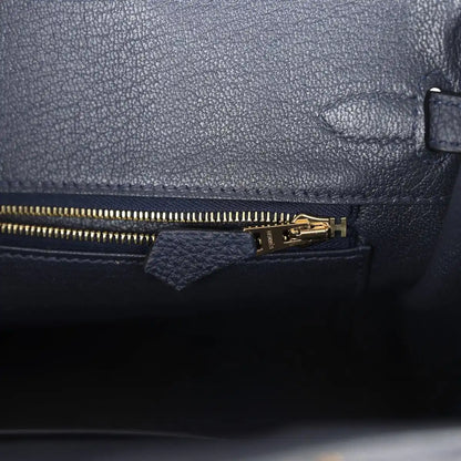 Hermes Birkin 25 handbag with dark blue leather zipper pocket and gold zipper pull.