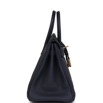 Hermes Birkin 25 handbag in dark blue leather with top handles, viewed from the side.