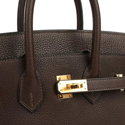 Brown leather handbag strap detail with gold-tone clasp and stitching