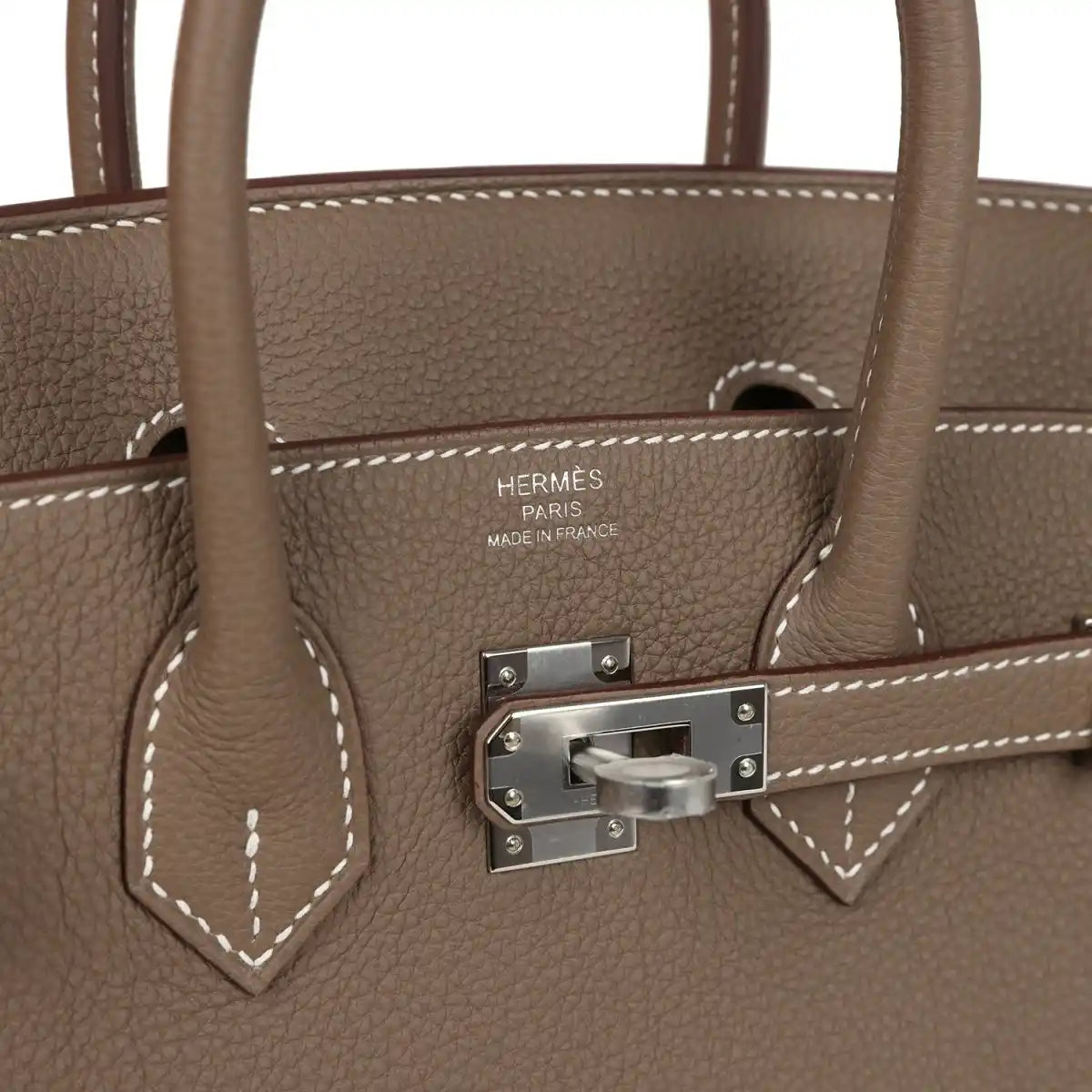 Hermes Birkin 25 handbag close-up of taupe leather, front clasp, and stitched handle trim