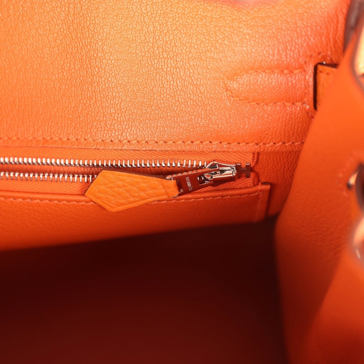 Orange leather Birkin 25 handbag interior zipper pocket with small tag and pull tab