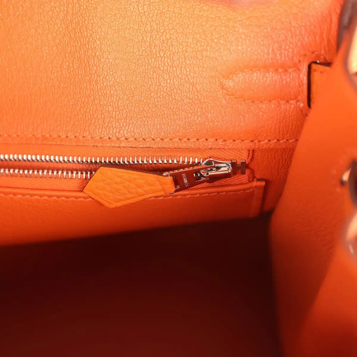 Orange leather Birkin 25 handbag interior zipper pocket with small tag and pull tab