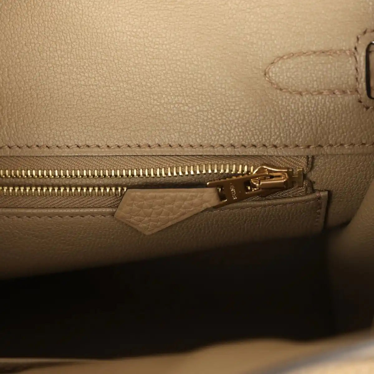 Beige leather handbag interior close-up of gold zipper and leather tab