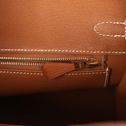 Tan leather handbag close-up of zipper and small pocket with gold-tone pull hardware.