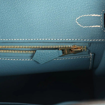 Teal-blue handbag interior zipper with gold-tone pull and small leather tab
