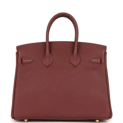 Burgundy leather handbag back panel with hanging straps and gold feet.