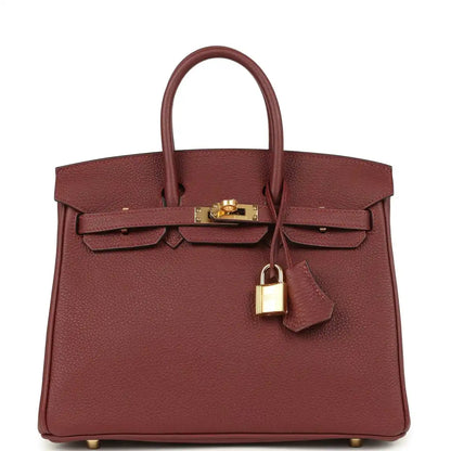 Burgundy leather top-handle handbag with gold hardware, front flap and turn-lock.