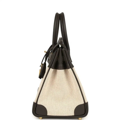 Small two-tone handbag with dark leather handles, beige canvas body and gold-tone lock charm