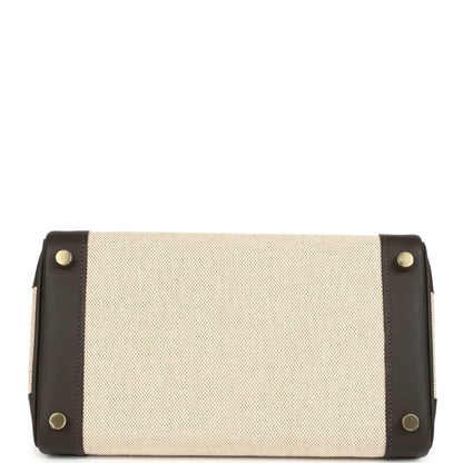 Rectangular handbag with beige canvas front and dark leather corners, gold-tone button studs