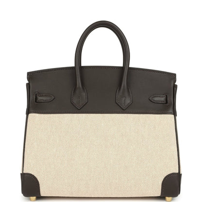Two-tone handbag with dark leather handles, beige canvas body, gold-tone feet and trim