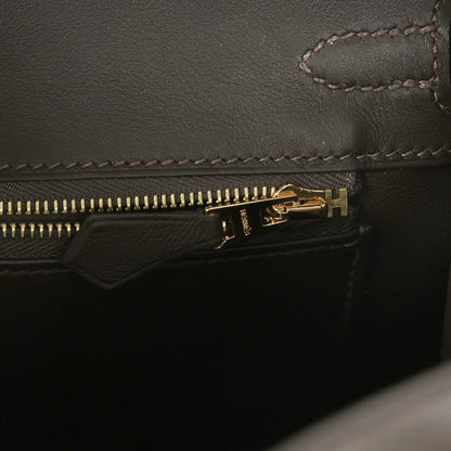 Dark leather handbag zipper with gold-tone zipper pull and stitched edge detail