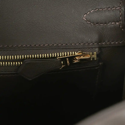 Dark leather handbag zipper with gold-tone zipper pull and stitched edge detail