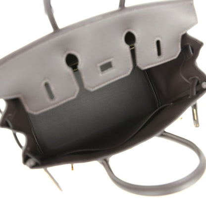 Handbag interior with dark lining, stitched leather tabs, and logo patch on back wall