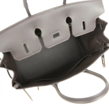 Handbag interior with dark lining, stitched leather tabs, and logo patch on back wall
