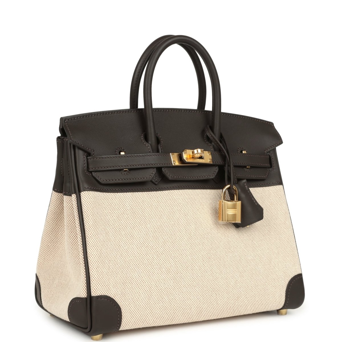 Two-tone handbag with dark leather trim, beige canvas body, gold-tone lock on top flap