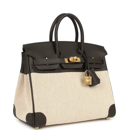 Two-tone handbag with dark leather trim, beige canvas body, gold-tone lock on top flap