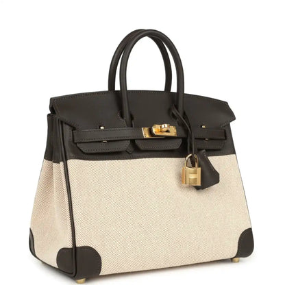 Two-tone handbag with dark leather trim, beige canvas body, gold-tone lock on top flap