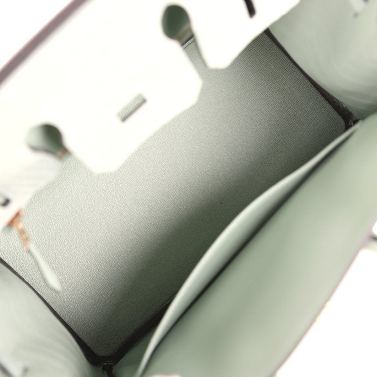 Light green handbag interior showing smooth lining, stitched edges, and open top opening