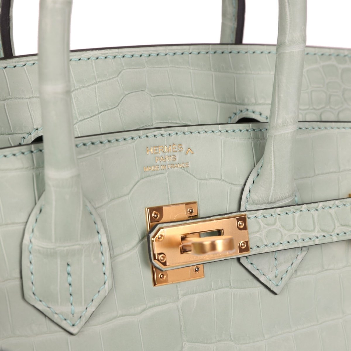 Light green croc-embossed handbag interior with gold turn-lock hardware and edge stitching