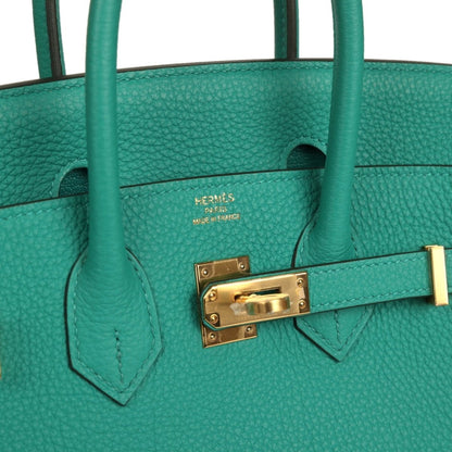 Green leather interior panel with gold hardware clasp and stitched divider