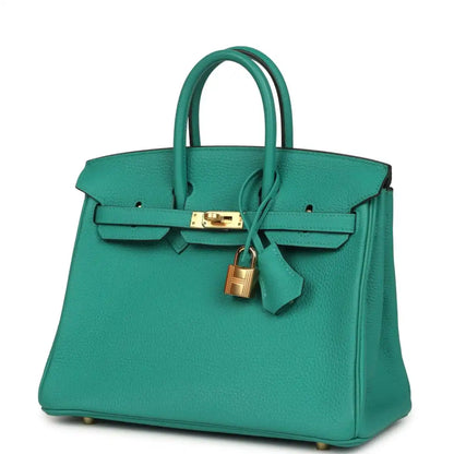 Green leather handbag with top handles, front strap clasp and gold lock charm