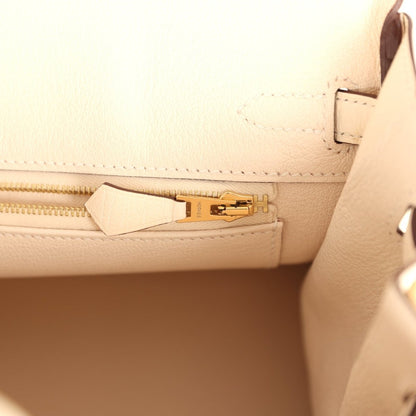 Nata ostrich handbag interior pocket with strap, gold-tone zipper pull, and stitching.