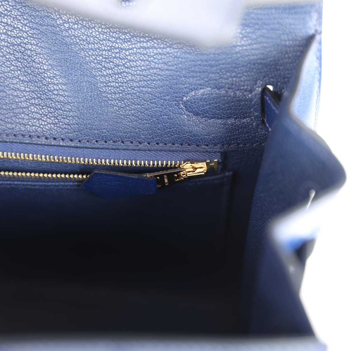 Blue handbag interior with gold zipper pull and fine stitching near seam