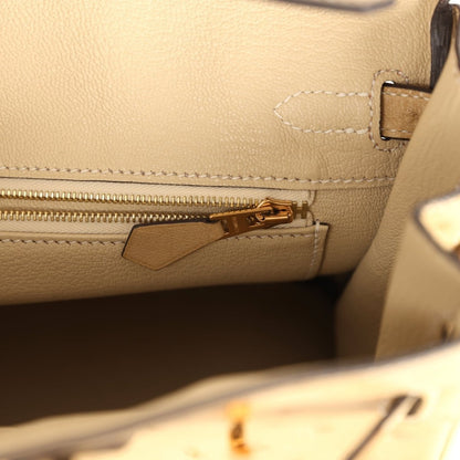 Tan ostrich leather handbag interior with gold zipper pull and stitched pocket edge.