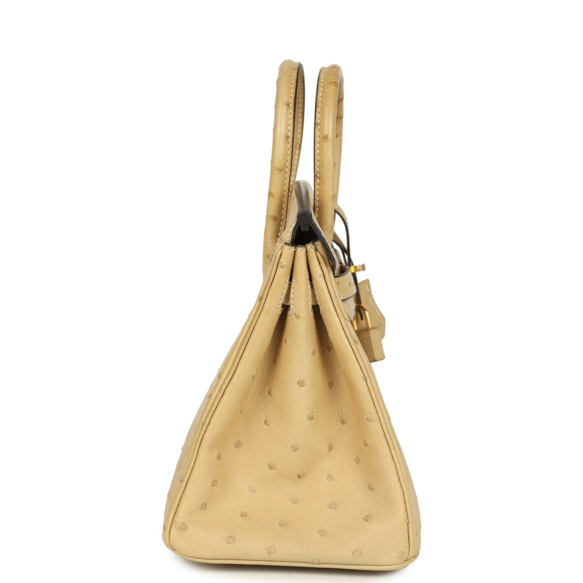 Tan ostrich leather handbag viewed from the side, with top handles and hanging tassel.